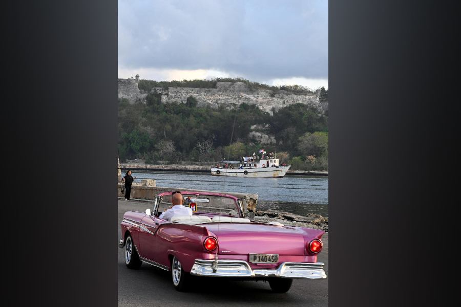 A vintage car drives by a boat of activists and members of a flotilla from Mexico arrive at Havana's bay, March 24, 2026
