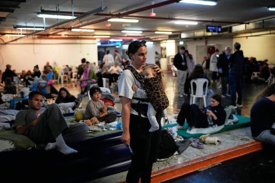Leah Guttmann holds her son, Teddy, as other people take shelter in an underground parking garage while air-raid sirens warn of incoming missiles launched by Iran toward Tel Aviv, Israel, Sunday, March 1, 2026
