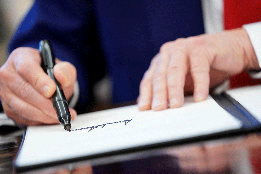 FILE PHOTO: U.S. President Donald Trump writes his signature, as he signs executive orders and proclamations in the Oval Office at the White House in Washington, D.C., U.S., April 9, 2025.