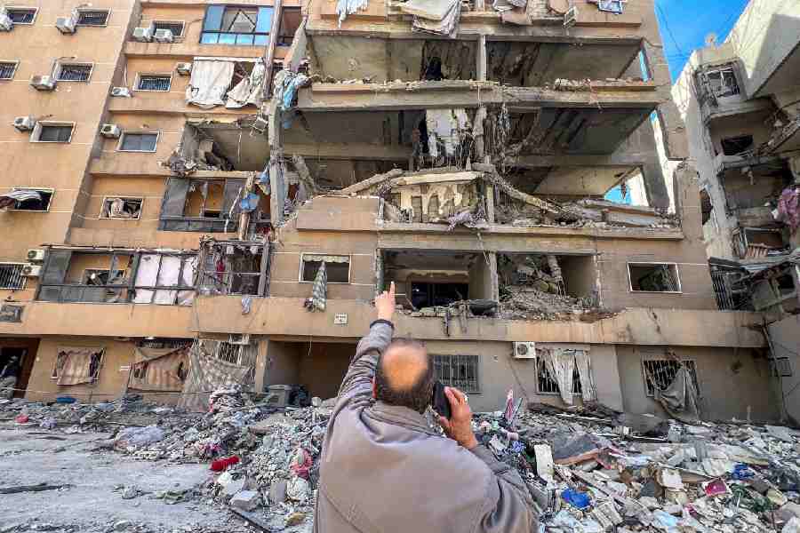 A man points at a building damaged by Israeli strikes, amid escalating hostilities between Israel and Hezbollah, as the US-Israeli conflict with Iran continues, in Beirut\\\'s southern suburbs, Lebanon, March 28, 2026. Picture taken with a mobile phone.