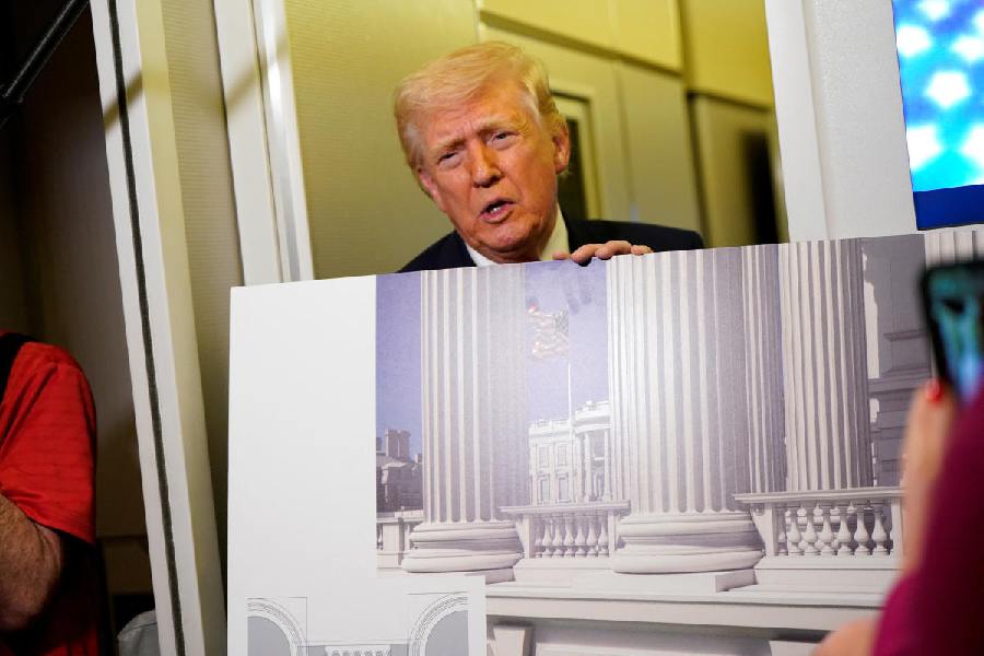 US President Donald Trump holds up renderings of the planned White House ballroom, aboard Air Force One