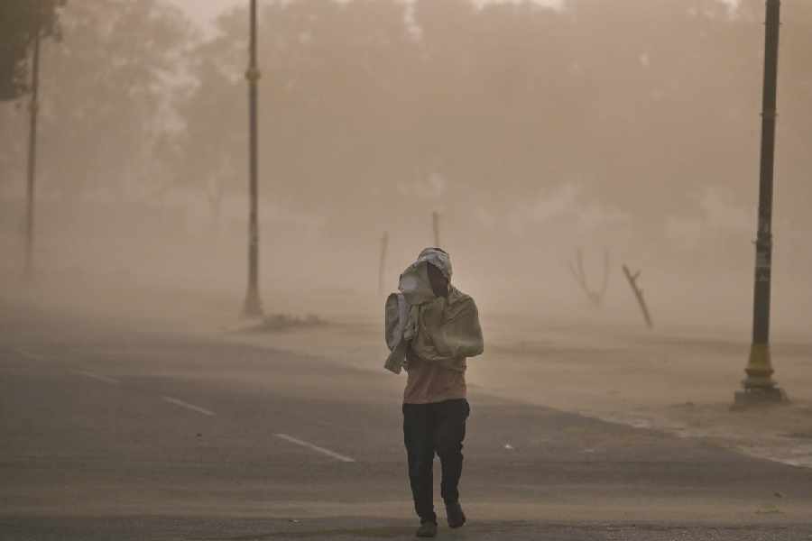 A commuter covers himself with a scarf as he walks during a dust storm