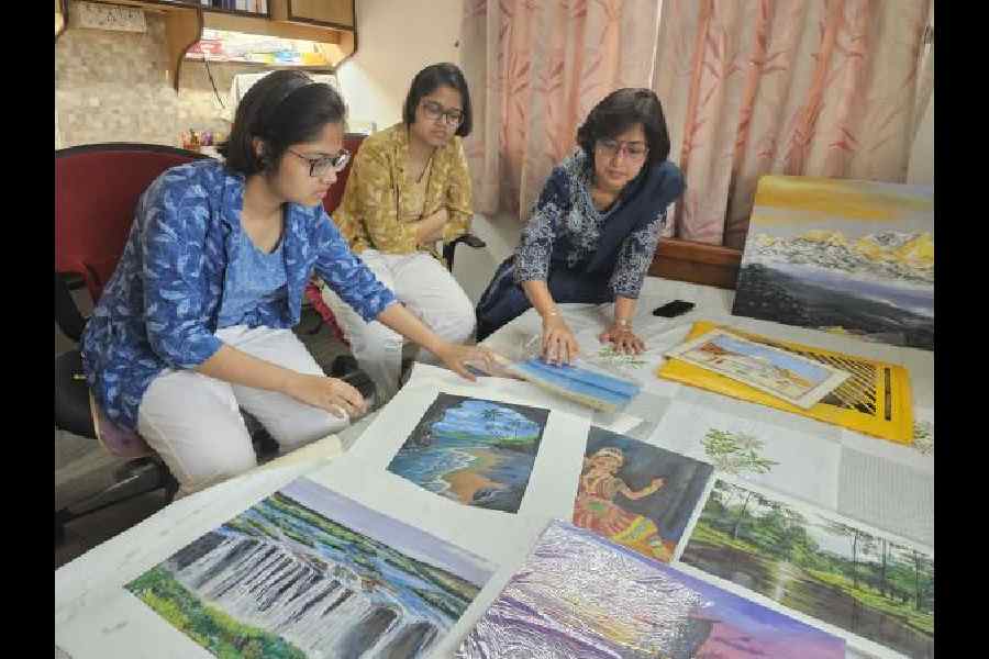 CBSE topper Anisha Ghosh (left) shows paintings done by her and her twin sister Anishka (centre). Mother Poulomi Ghosh is also in the frame.  