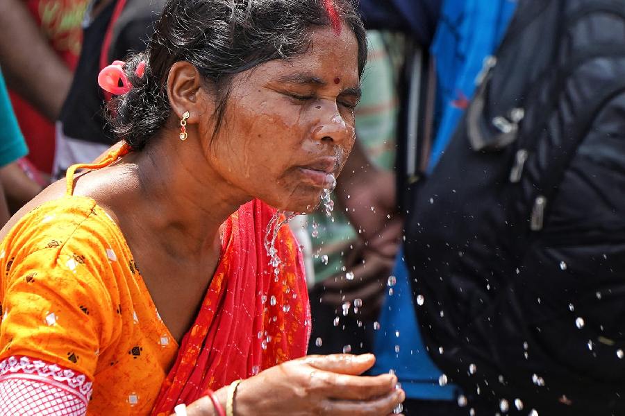 A woman at Esplanade splashes water on her face to escape the sweltering weather