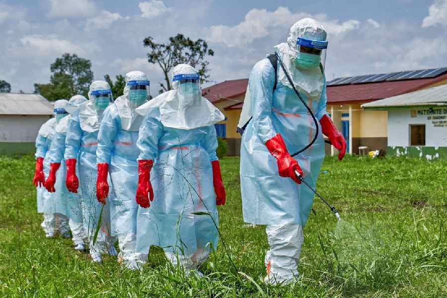 Red Cross workers walk in a formation as they disinfect Rwampara general hospital before handling the body of a person who died of Ebola, as aid agencies intensify efforts to contain a new Ebola outbreak involving the Bundibugyo strain, in Rwampara outside Bunia, Ituri province, Democratic Republic of Congo, May 21, 2026.