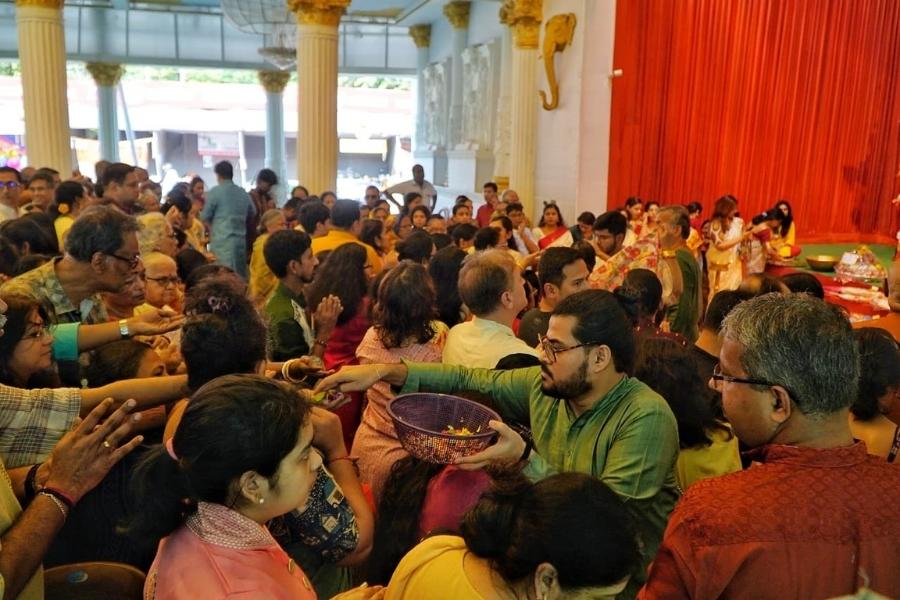 Men in stylish kurtas and women in festive saris gathered around the altar to receive offerings and floral petals for the ritual.