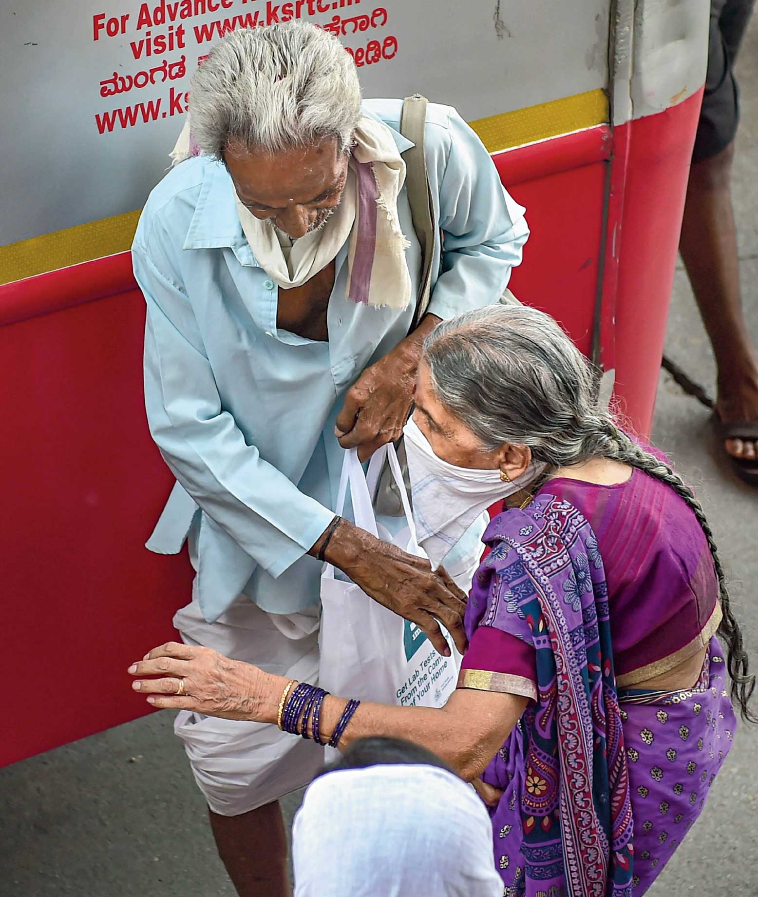 An elderly migrant couple prepare to board a bus in Bangalore on Sunday. 