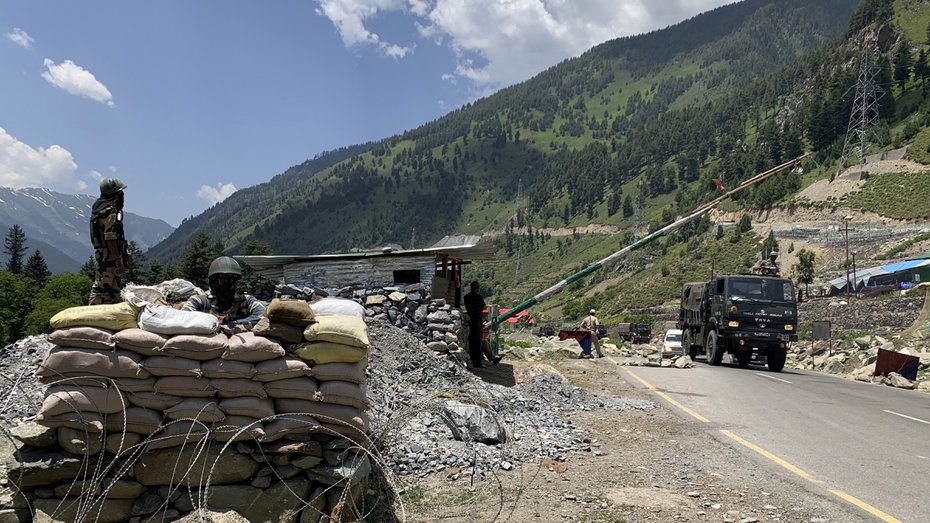 Soldiers keep guard as an army convoy moves on the Srinagar-Ladakh highway northeast of Srinagar on June 20