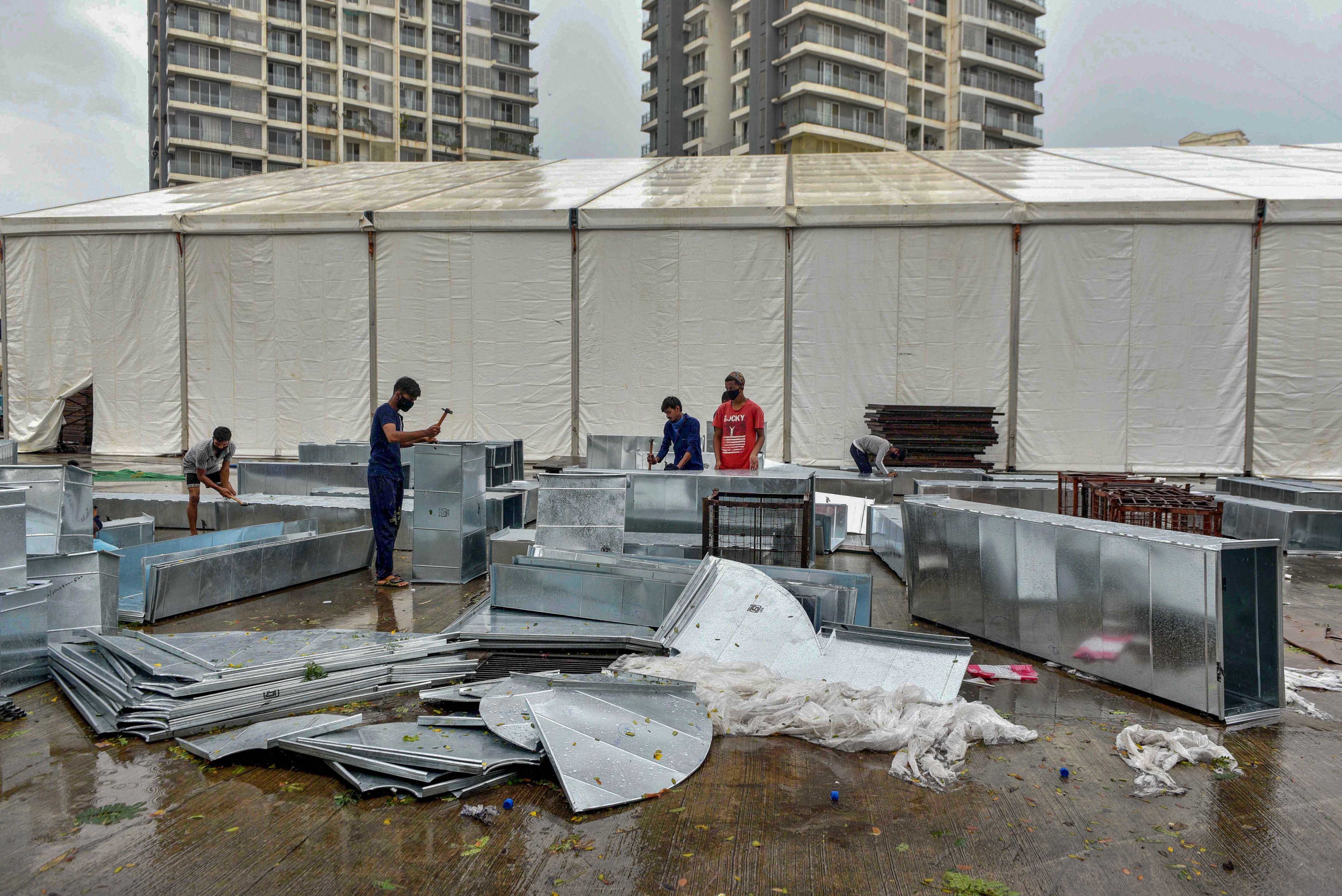 Workers carry material to build an quarantine and hospital facility for treating critical Covid-19 patients, at RTO Kandarpada in Mumbai, Thursday, June 4, 2020.