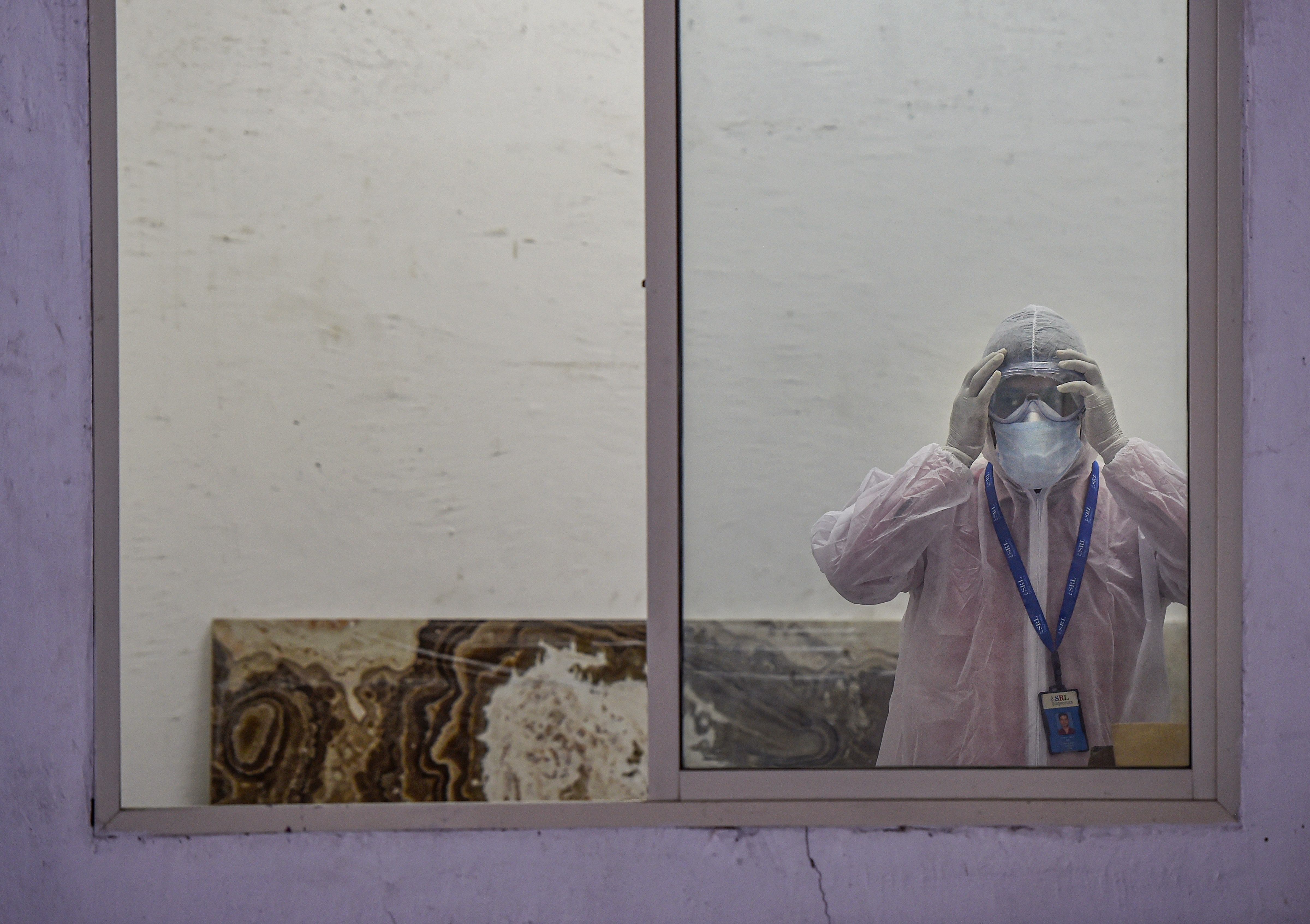 A medic wears a protective suit in the waiting room of the first drive-through sample collection site for possible COVID-19 patients, during the nationwide lockdown to curb the spread of coronavirus, at Lower Parel in Mumbai, Monday, April 13, 2020.