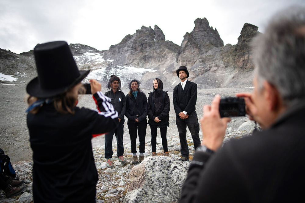 Climate change activists, wearing dark clothing, pose near the 'dying' glacier of Pizol mountain in Wangs, Switzerland, on Sunday