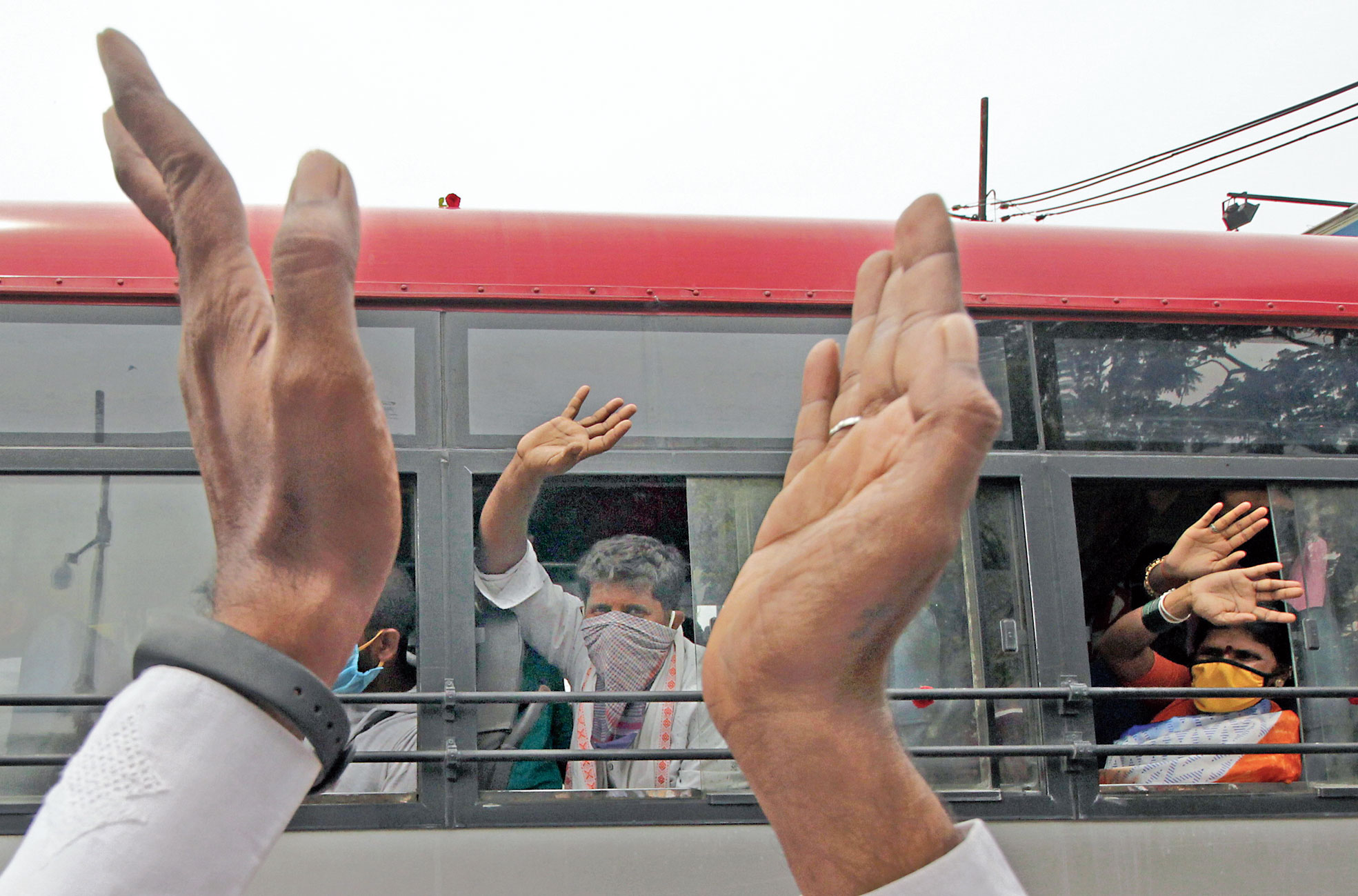 Migrants wave as they leave for their home states in a bus from Bangalore on Thursday. 