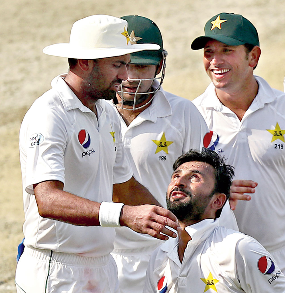 Bilal Asif of Pakistan celebrates with teammates after dismissing Tim Paine toclaim his fifth wicket,  in Dubai on Tuesday. 