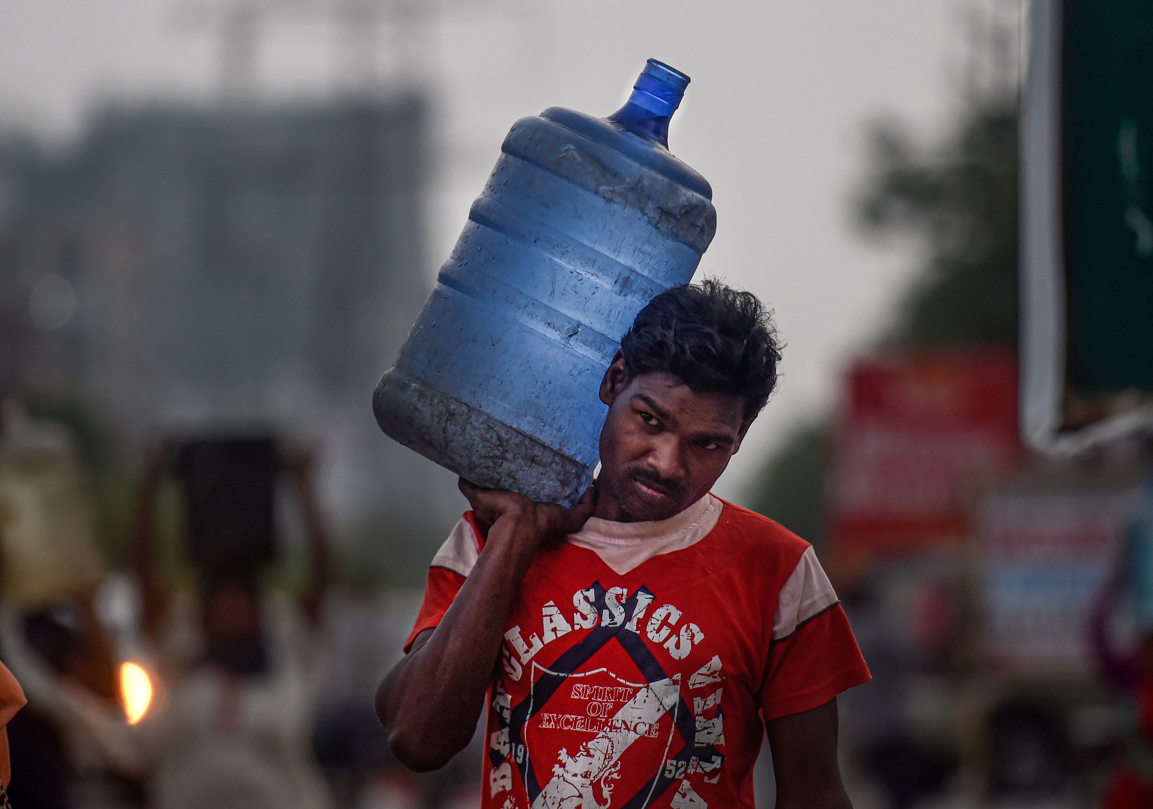 A man carries a container filled with drinking water during the nationwide lockdown, imposed in wake of the coronavirus pandemic, in Ghaziabad, Monday, April 27, 2020.