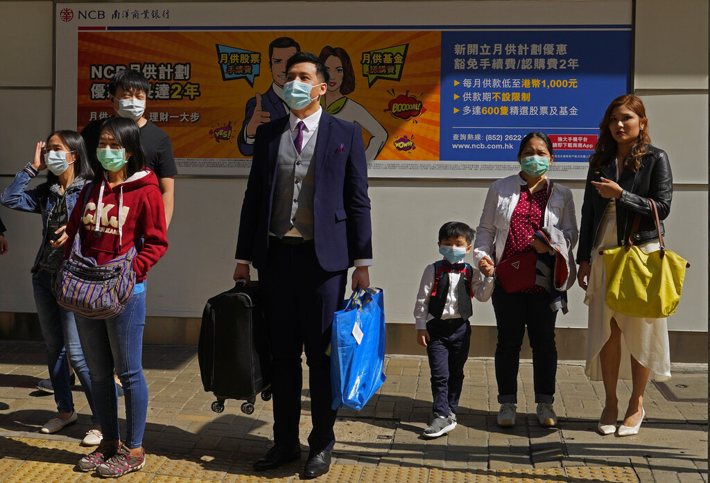 People wearing face masks wait at a pedestrian cross walk Hong Kong on Saturday, February 22, 2020