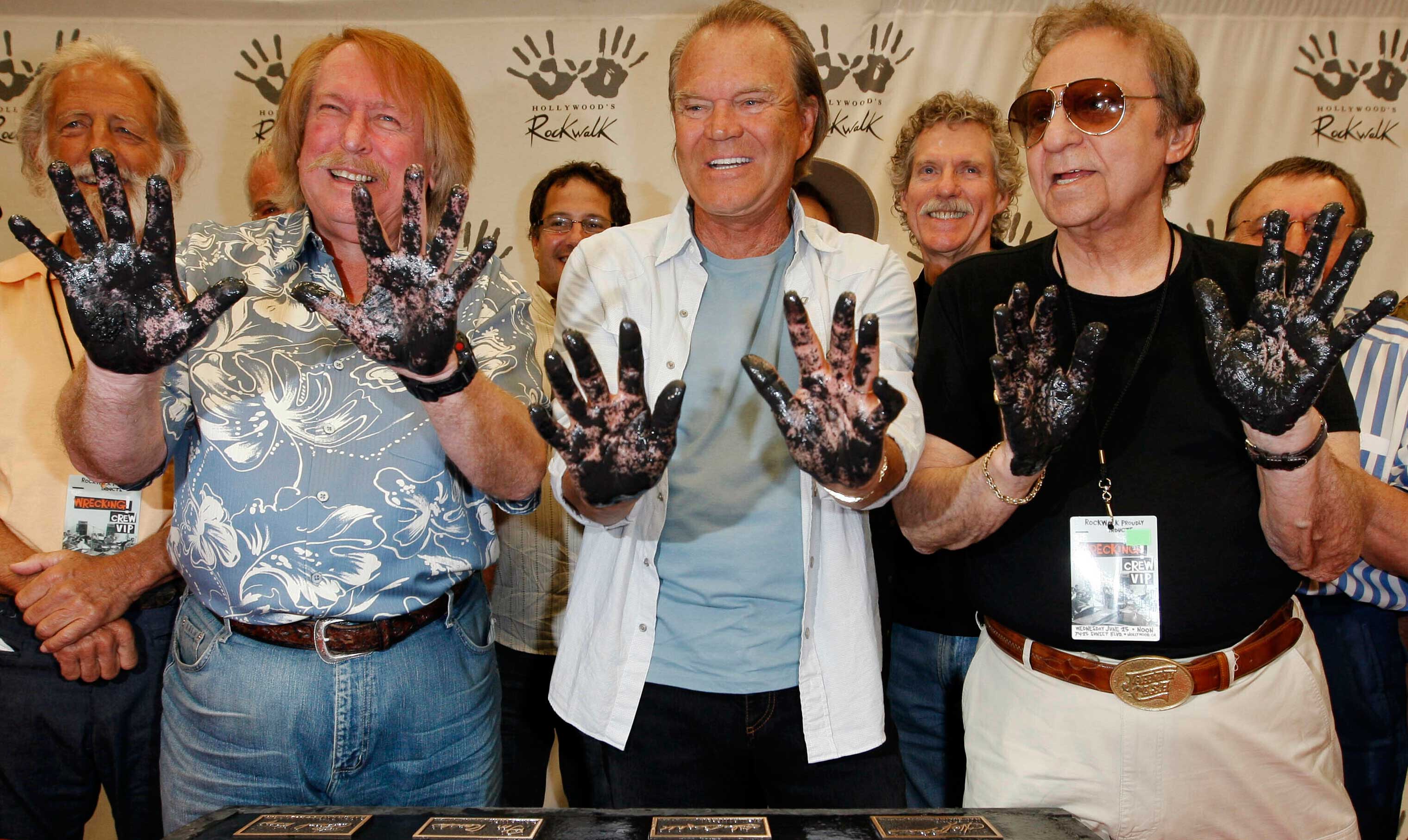 (From left) Don Randi, Glen Campbell and Hal Blaine, representing session musicians known as 'The Wrecking Crew', hold up their hands after placing them in the cement following the induction ceremony for Hollywood's RockWalk in Los Angeles, on June 25, 2008. 