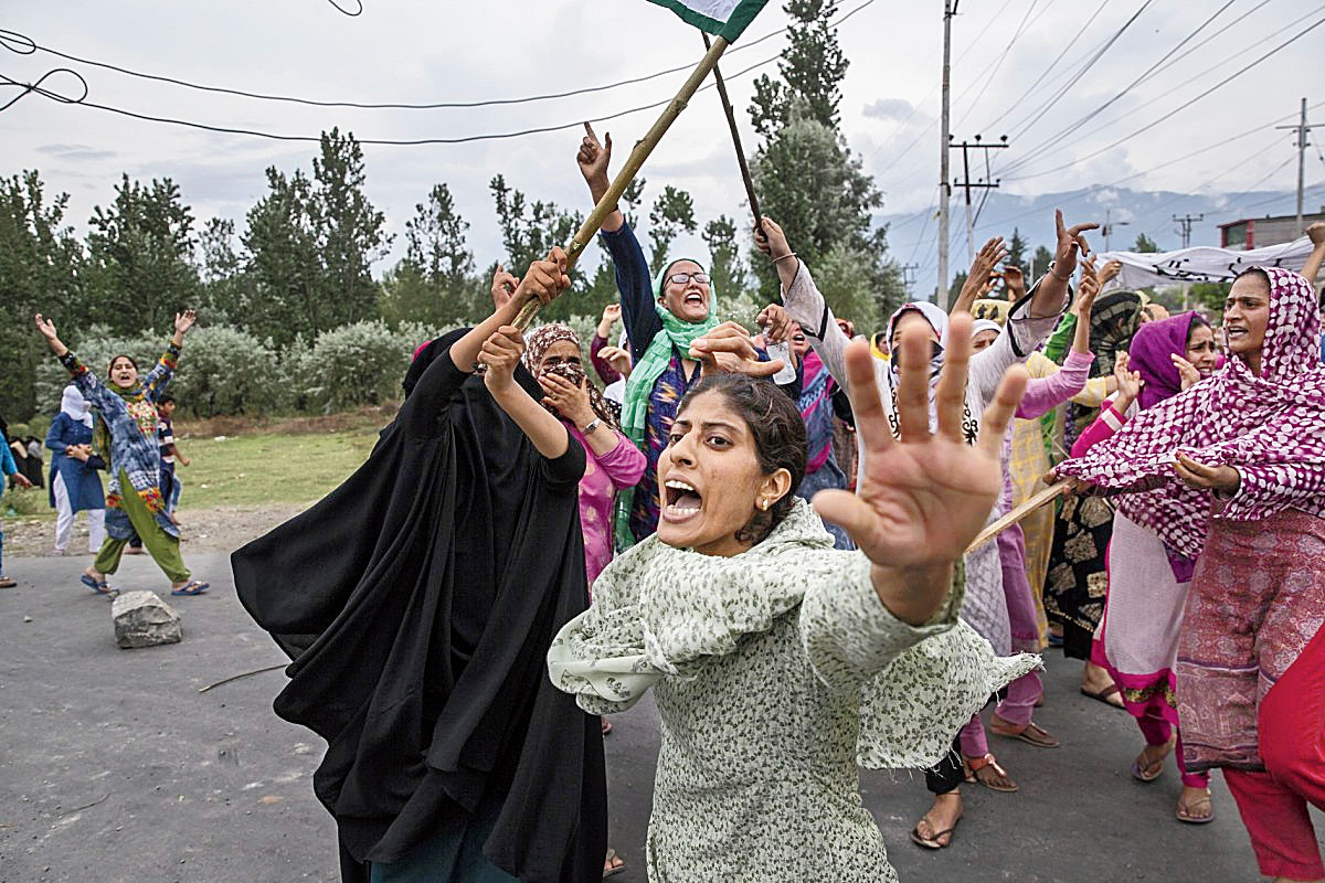 Women shout slogans as policemen fire teargas and live ammunition in the air to stop a protest march in Srinagar on  August 9, 2019.