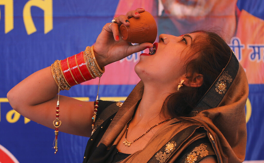 An Indian Hindu woman drinks cow urine during an event organized by a Hindu religious group to promote consumption of cow urine as a cure for the new coronavirus in New Delhi, India, Saturday, March 14, 2020.