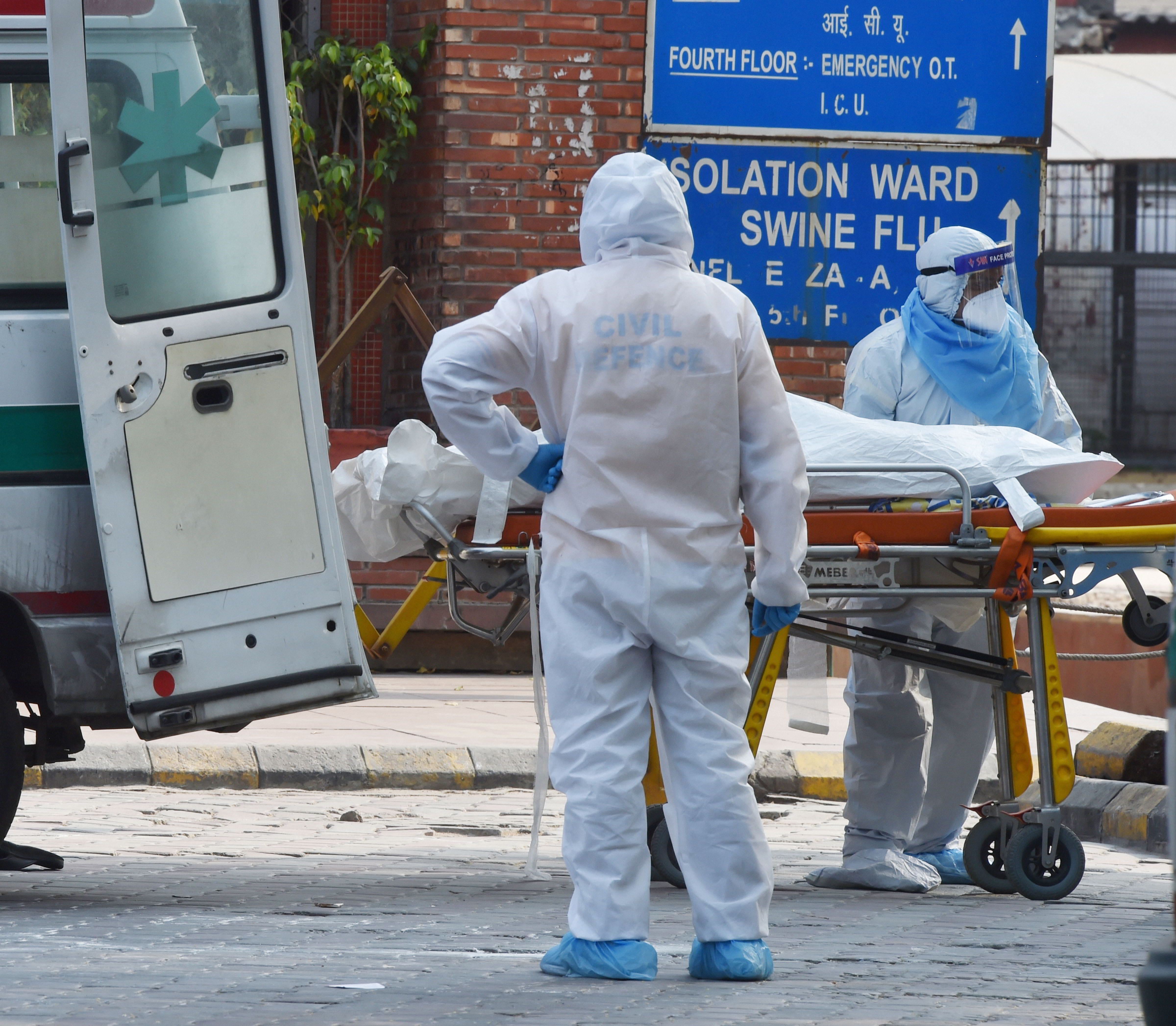 Health workers wearing protective suits shift to a van the body of a coronavirus victim, at LNJP Hospital in New Delhi, Thursday, April 30, 2020.