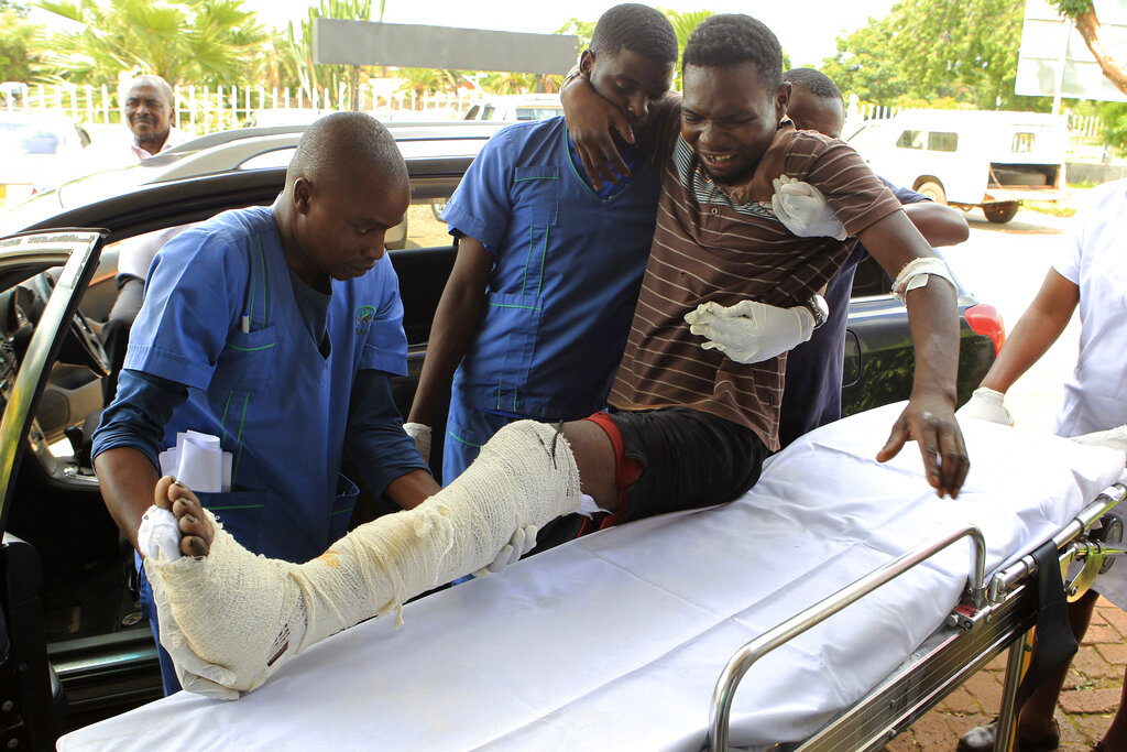 An injured man is helped at a private hospital after an alleged assault by a group of uniformed soldiers in Harare on Thursday.