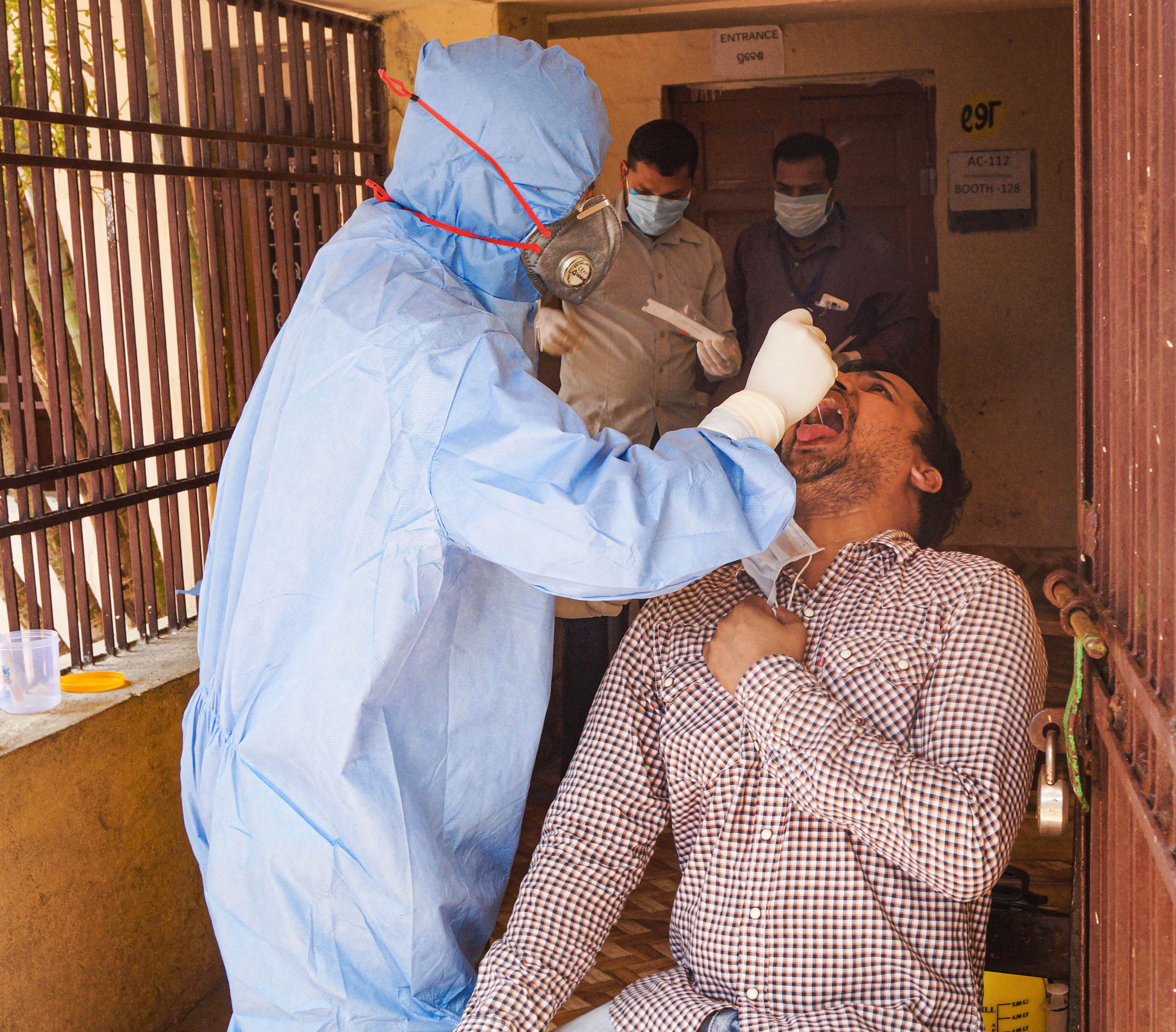 A medic collects swab sample of a person for COVID-19 test at a sample collection centre, during the nationwide lockdown imposed in wake of the coronavirus pandemic, in Bhubaneswar, Monday, April 13, 2020.