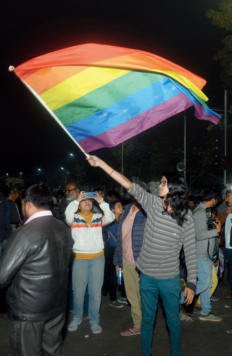 6.23pm: The protester continues to hold the rainbow flag in the evening
