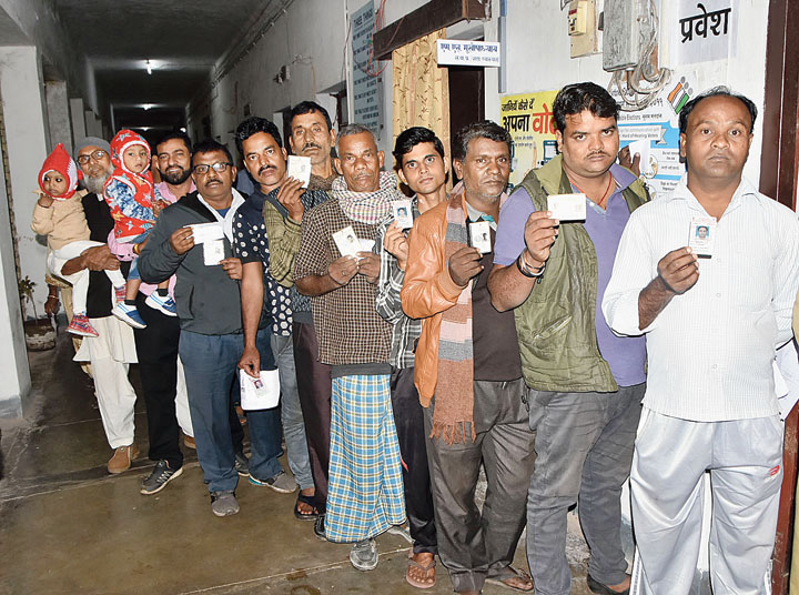 Voters wait to cast their votes at a polling booth in Dhanbad on Monday. 