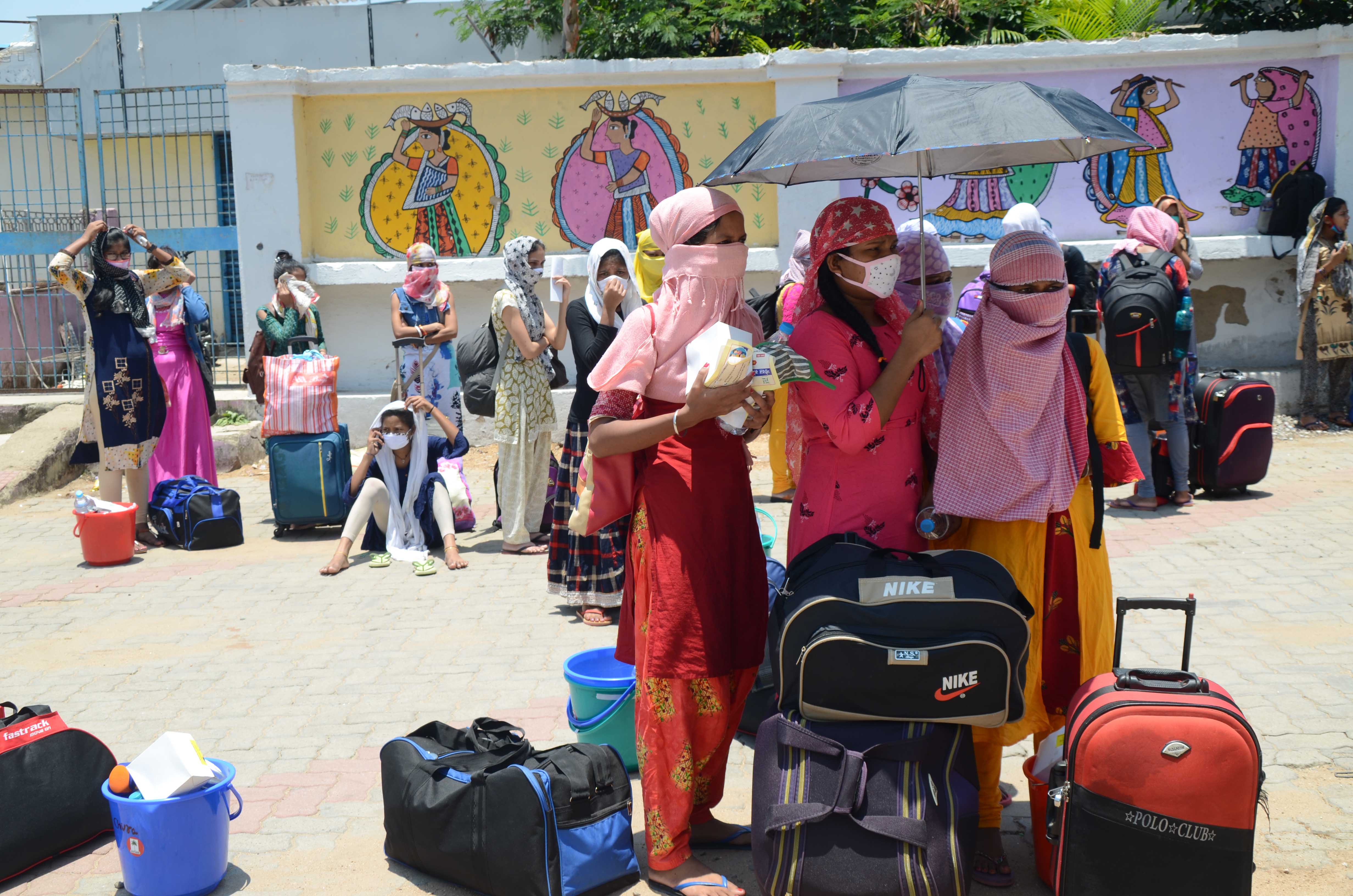 A group of women, as many as 600 got off from the train in Ranchi, wait for their turn to board buses to take them home.