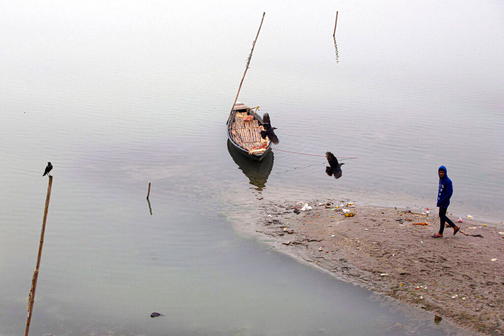 Birds fly over an anchored boat in the river Brahmaputra on a cold winter morning in Guwahati on January 3, 2020.
