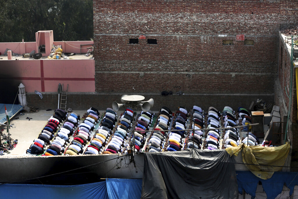 Muslims offer prayers on the roof of a fire-bombed mosque in New Delhi, on Friday