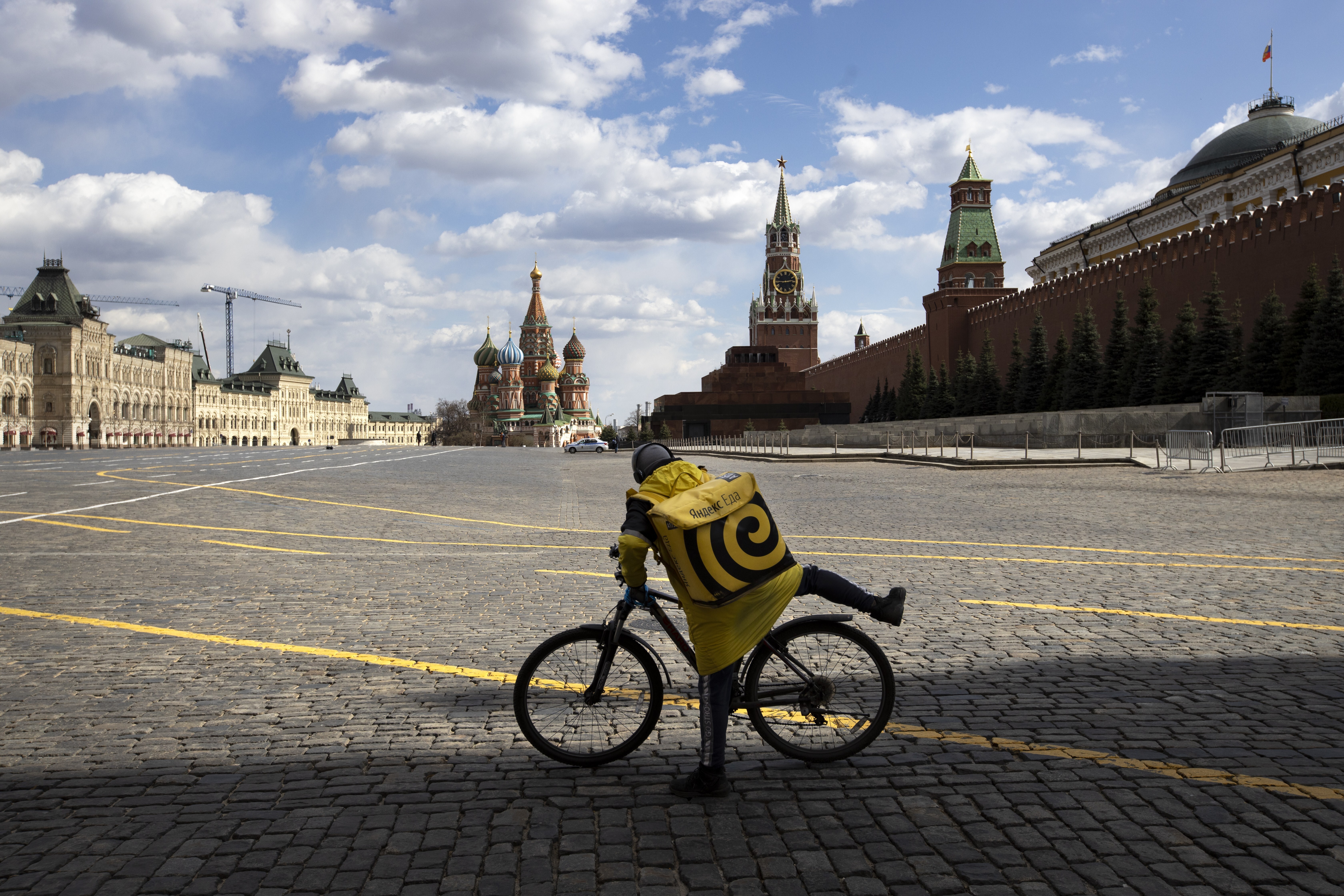 A food delivery courier rides his bicycle on an empty Red Square in Moscow, Russia