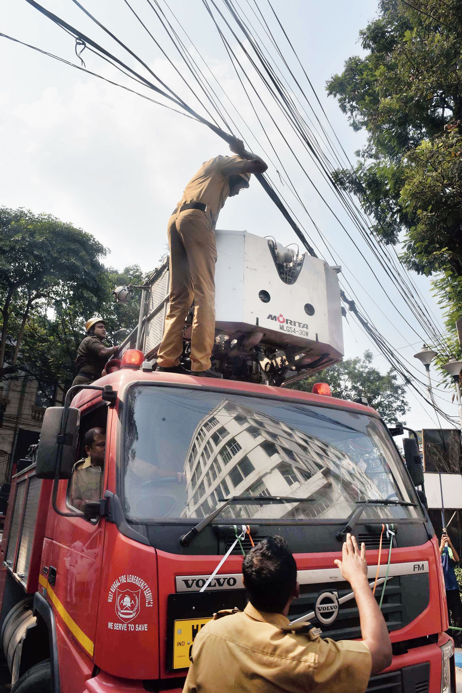 Fire officers remove overhead wires for fire engines to reach the building.