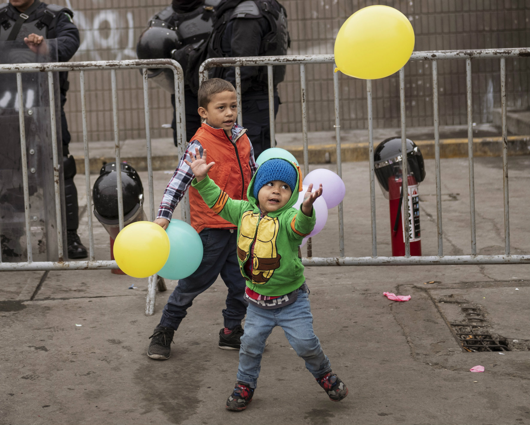 Children play with balloons outside an empty warehouse used as a shelter set up for migrants in downtown Tijuana, Mexico.