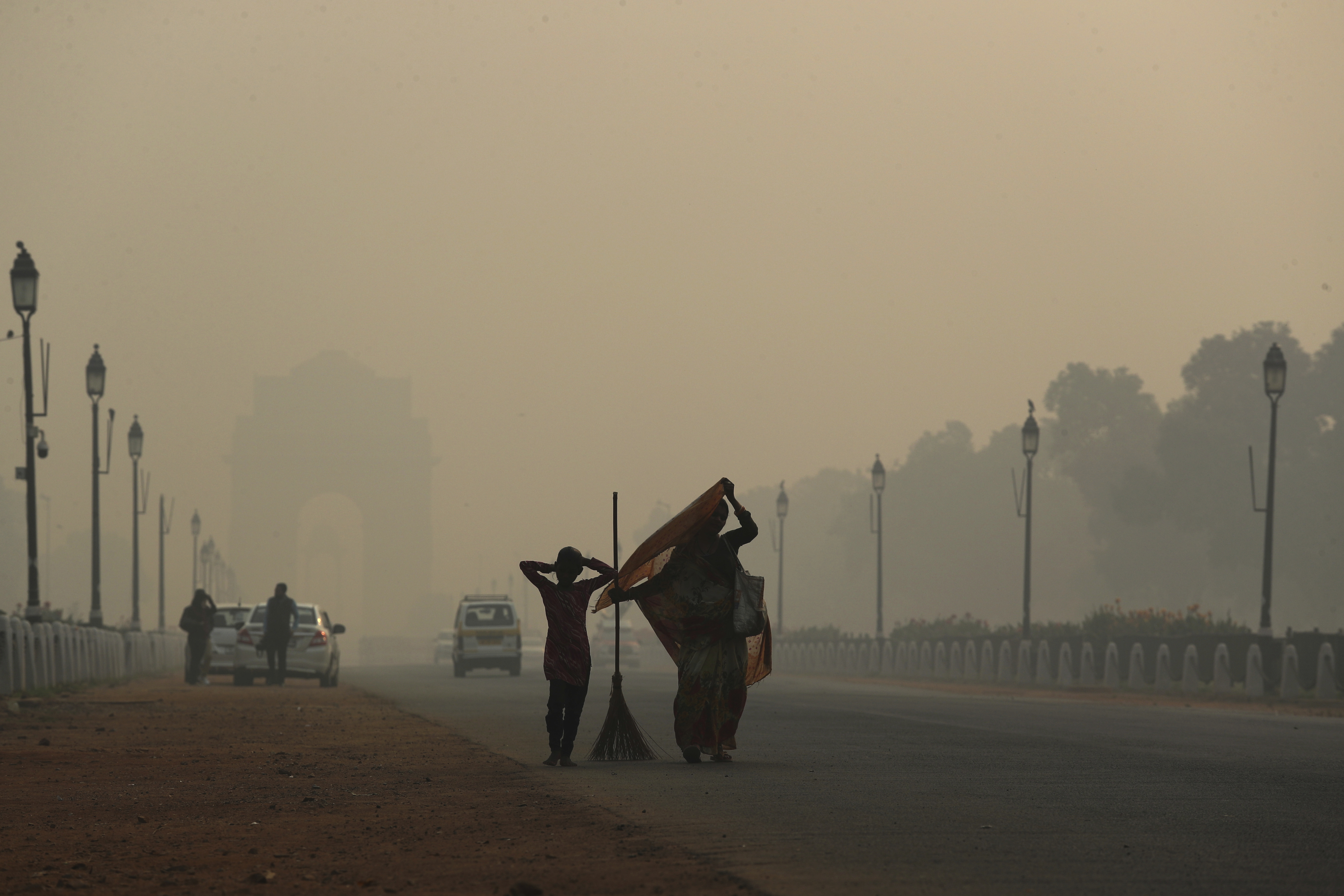 A municipal worker with her daughter leaves after sweeping the India Gate area in Delhi, on Thursday, November 8, as a thick haze of pollution hangs over the city the day after Diwali.
