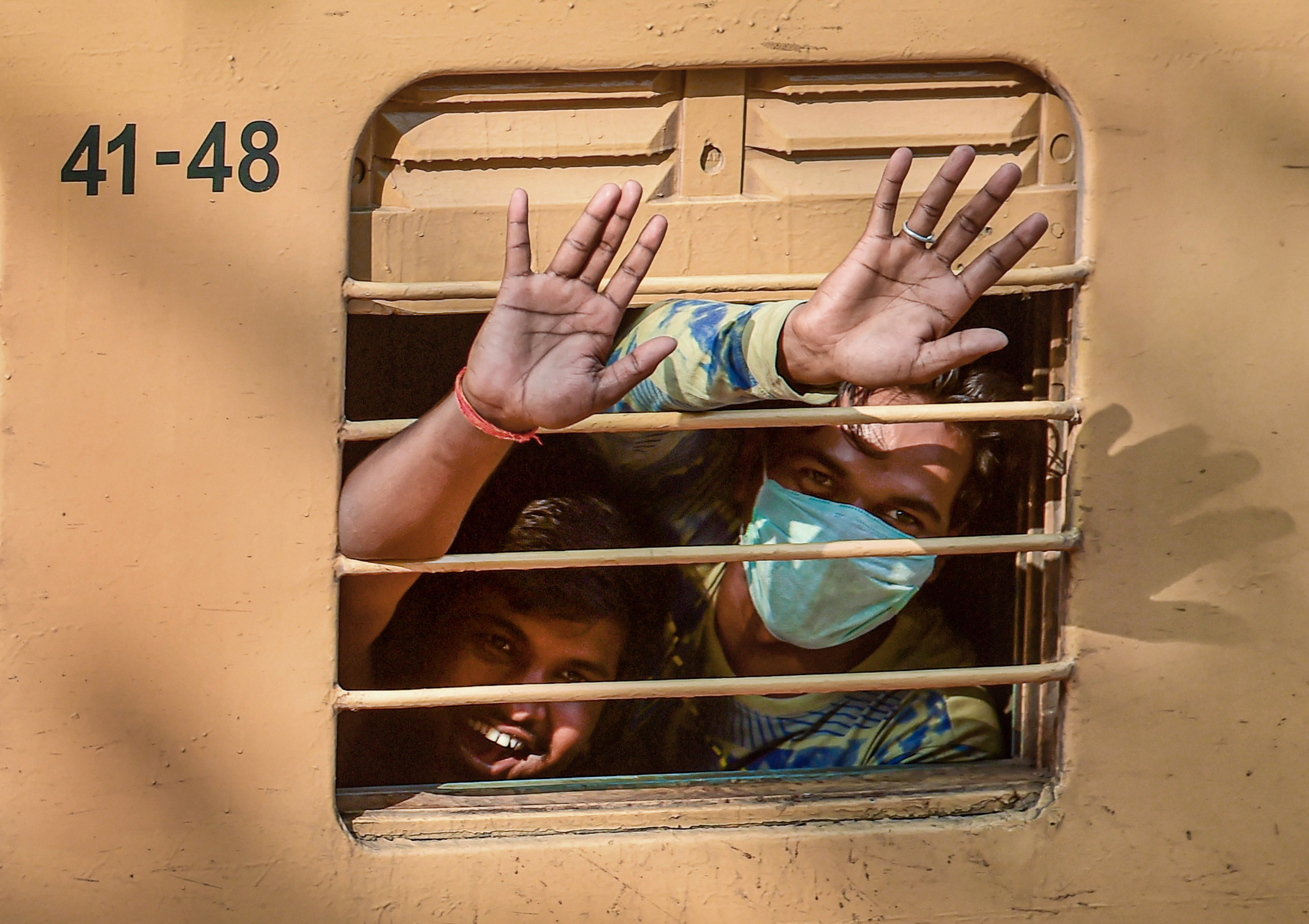 Migrant people wave as they prepare to travel in a special train the Chikkabanavara railway station for their native places in Uttar Pradesh, amid ongoing Covid-19 lockdown, in Bengaluru, Friday, May 8, 2020.