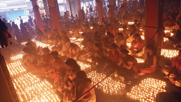 Women devotees light earthen lamps during Sandhipuja at Shanti Sabha at Kumarpara in Guwahati on Sunday.