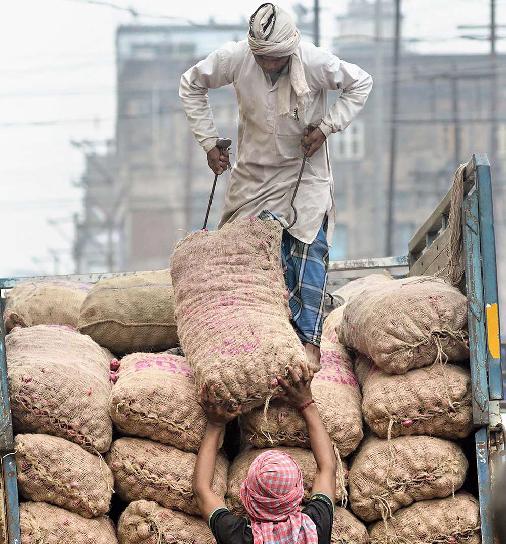 Labourers unload sacks of onions from a truck in a vegetable market in Guwahati