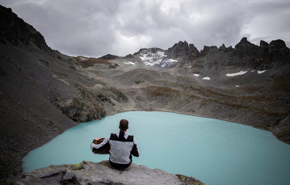 A hiker plays his accordion near the Wildlake and the Pizol glacier during a commemoration for the 'dying' glacier of Pizol mountain in Wangs, Switzerland, on Sunday