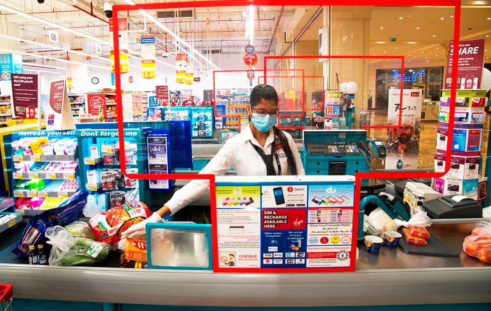 In this April 19, 2020 photo, cashier Valancy Fernandes of India, wearing a surgical mask and gloves to help prevent the spread of coronavirus, works at a Carrefour supermarket in Dubai, United Arab Emirates. 