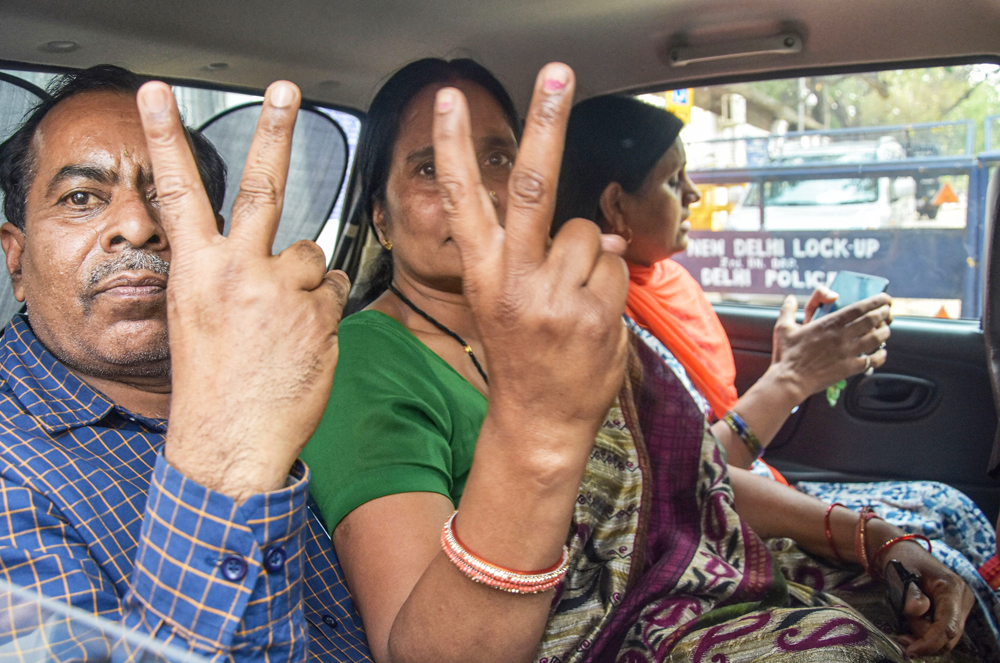 The 2012 Delhi rape case victim's mother and father flash the victory sign as they leave Patiala House court in New Delhi, Thursday, March 19, 2020. 
