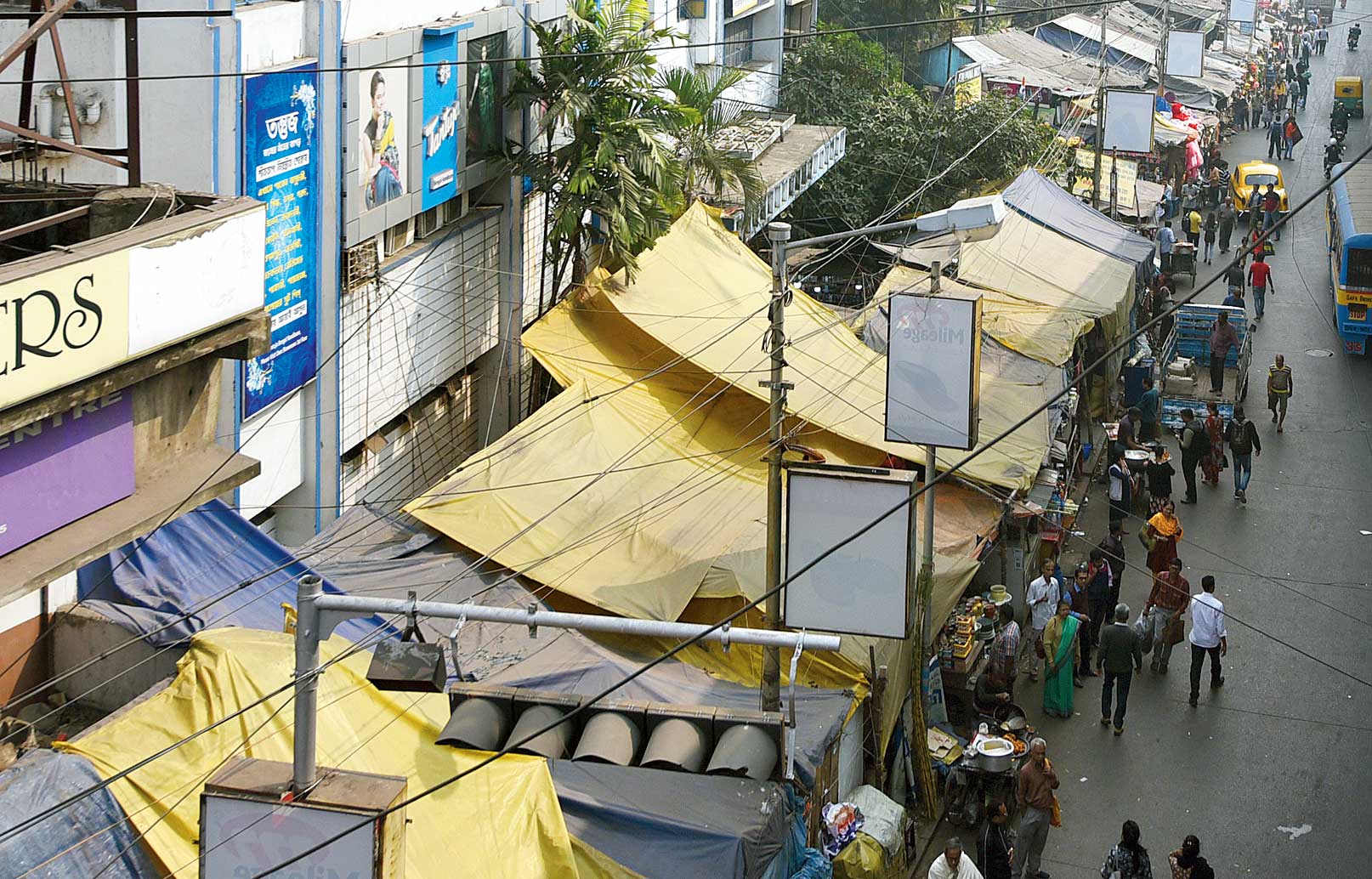 Tarpaulin and plastic sheets cover hawkers’ stalls on a Gariahat pavement. 


