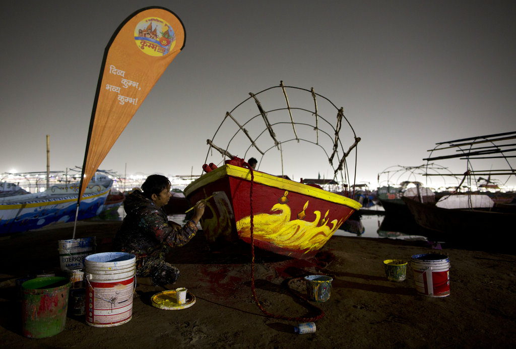 A man paints a boat ahead of Kumbh Mela under a gloomy sky. The dust plumes encompassing the Kumbh camp come from the sandy riverbanks, and not from construction, which is banned during the 55-day festival, according to Allahabad commissioner Ashish Goel.