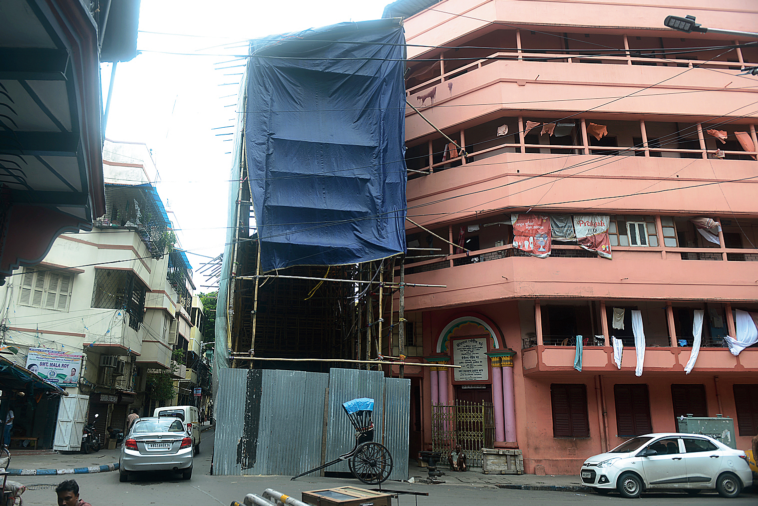A car squeezes past the 64 Pally Puja pandal.