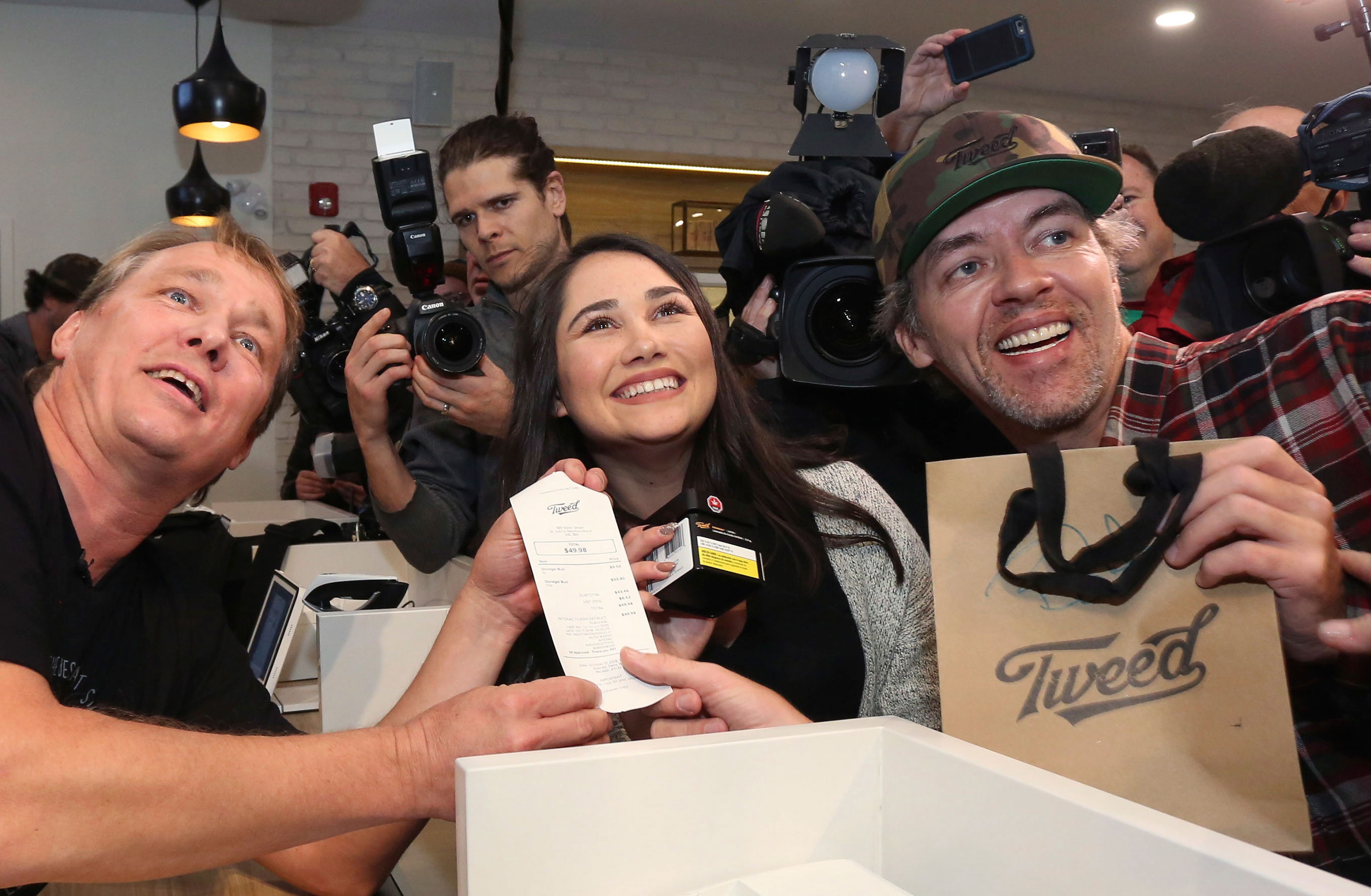 Canopy Growth CEO Bruce Linton, left to right, poses with the receipt for the first legal cannabis for recreation use sold in Canada to Nikki Rose and Ian Power at the Tweed shop on Water Street in St. John's N.L. at 12:01 am NDT on Wednesday. 