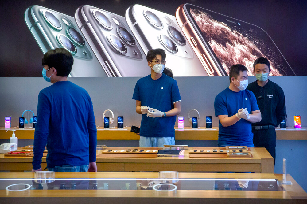 Employees wear face masks as they stand in a reopened Apple Store in Beijing on February 14, 2020.