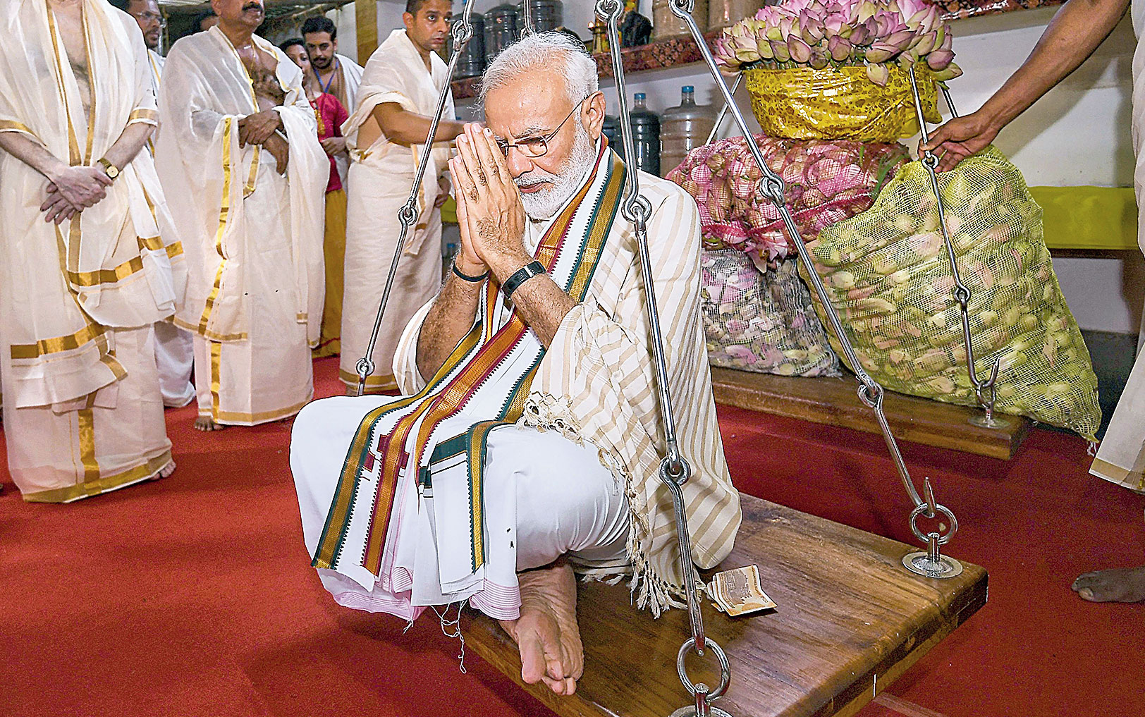 Prime Minister Narendra Modi takes part in Tulabharam, a ritual in which a devotee is weighed against an offering (in this case, lotus flowers), at the Lord Krishna temple in Guruvayur in Kerala on Saturday. 