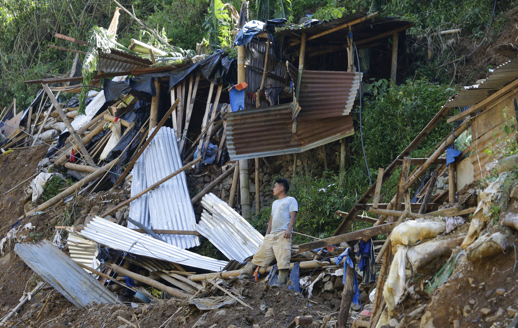 A resident stands beside toppled houses at the site where victims are believed to have been buried by a landslide after Typhoon Mangkhut lashed Itogon.