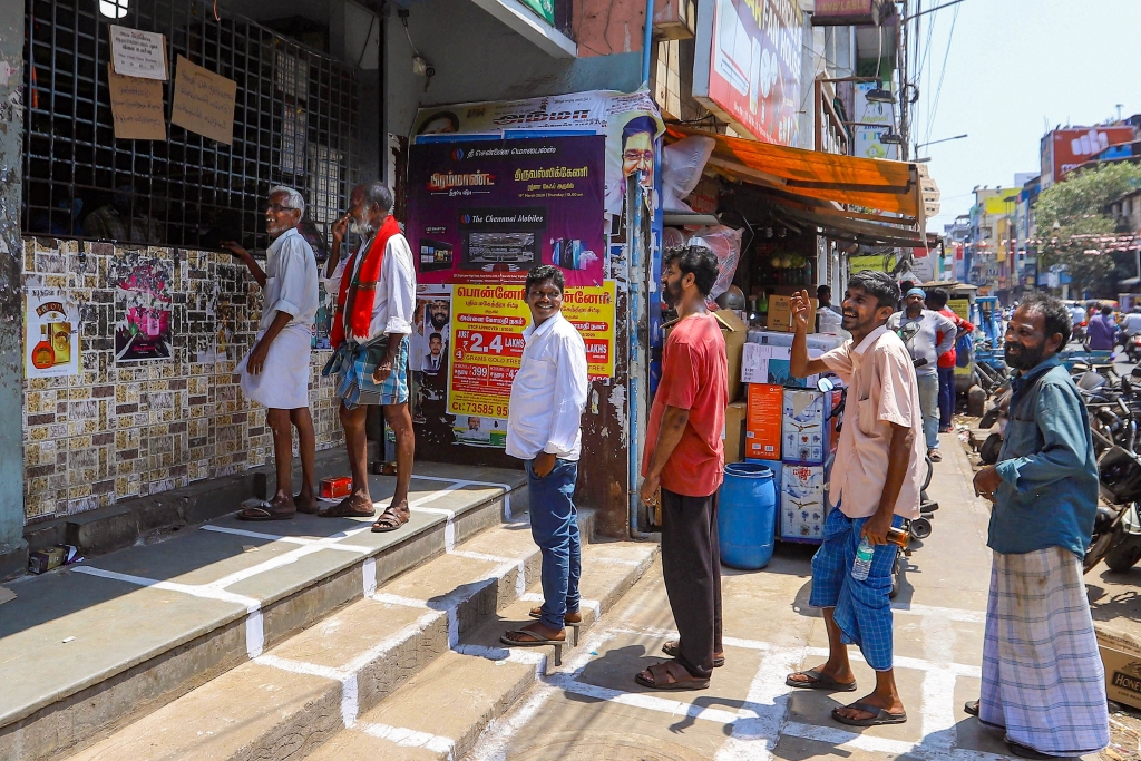 People maintain distance and stand in a queue to buy liquor from TASMAC outlet, in Chennai, on Saturday, March 21, 2020.