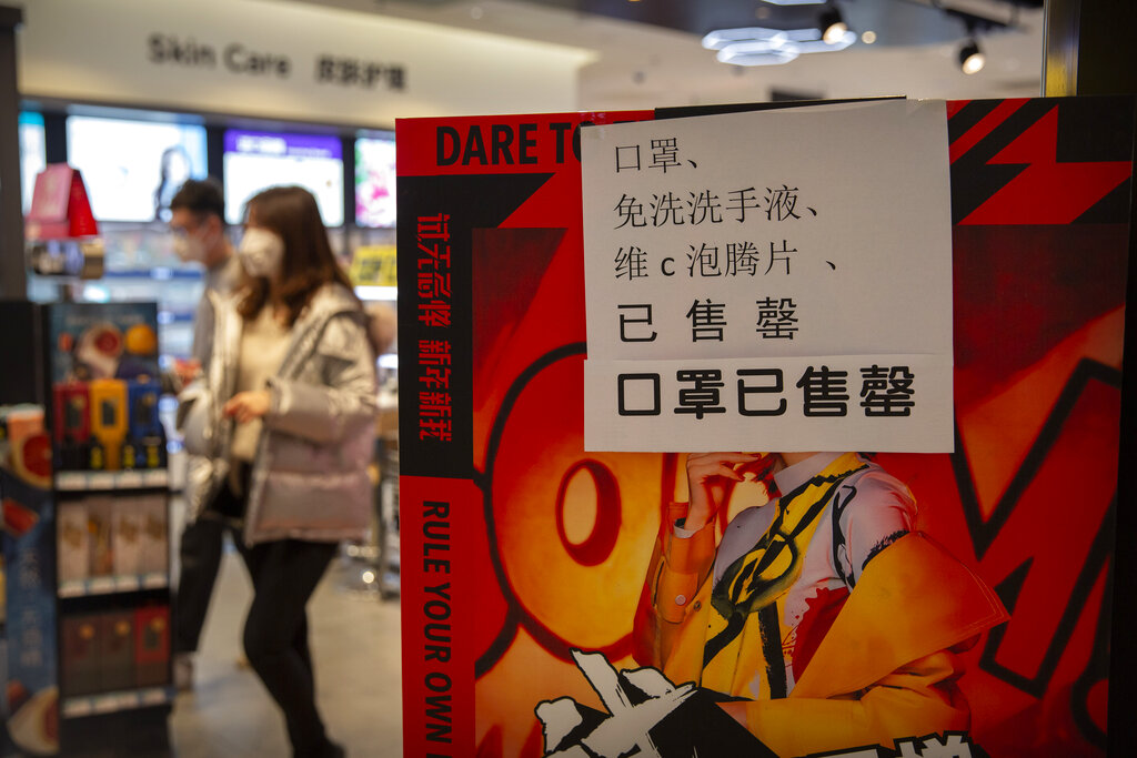 People walk past a sign at a drug store saying that it is sold out of face masks, hand sanitizer, and vitamin C in Beijing, on January 24, 2020