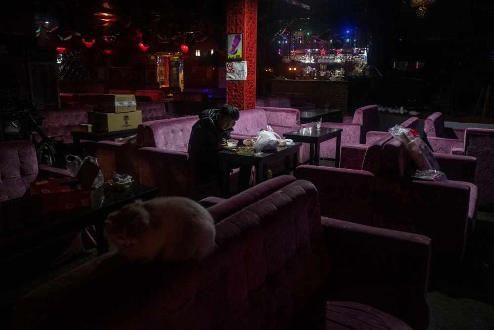 A lone man having dinner in a closed bar in a neighborhood of Beijing with a usually lively nightlife, Feb. 12, 2020